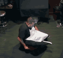 a man with a mask on his face is sitting on a stool