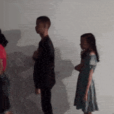 a girl in a green dress is standing next to a boy in a black suit