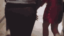 a woman in a red dress is holding a man 's hand in a blurry photo .
