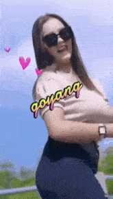 a woman wearing sunglasses has the word goyang written on her shirt