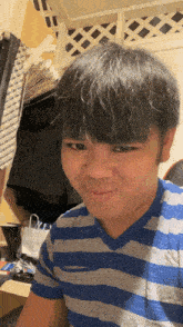 a man wearing a blue and gray striped shirt is smiling