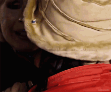 a close up of a person wearing a red jacket and a white hat with editsmalte written below it