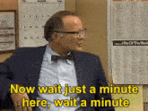 a man wearing glasses and a bow tie says now wait just a minute here wait a minute