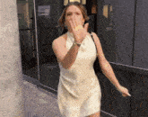 a woman in a white dress covering her mouth with her hand