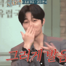 a man in a suit is covering his mouth with his hands in a foreign language