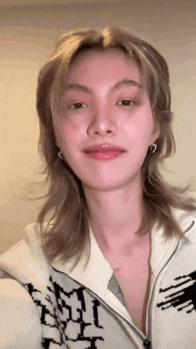 a woman wearing a sweater with the letter m on it looks at the camera