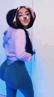 a woman wearing a purple hoodie and blue pants is standing in front of a mirror .