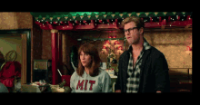 a man and a woman are standing next to each other and the woman has a mit sweatshirt on
