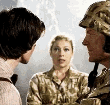 a man and a woman in military uniforms are talking to each other . the man is wearing a helmet .