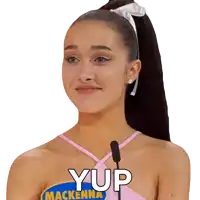 a woman with a ponytail is wearing a pink top with the word yup on it