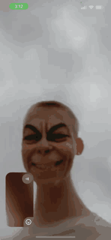 a phone screen shows a man with a strange face and the time is 3:12