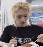 a young man with blonde hair is eating a plate of food with a fork and spoon .