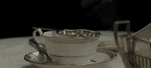 a cup and saucer on a table with a strainer in it