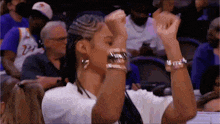 a woman is raising her fist in the air while sitting in the stands at a basketball game .