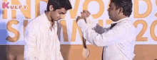 two men are shaking hands in front of a sign that says ' awards ' on it .