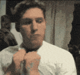a man in a white shirt is tying a tie