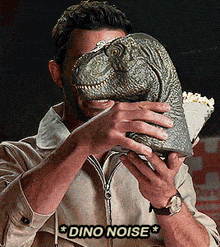 a man is holding a dinosaur head in front of his face with the words " dino noise " below it