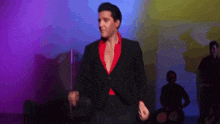 a man in a suit and red shirt is dancing on stage .