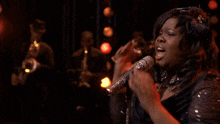 a woman is singing into a microphone with a band in the background