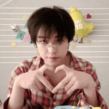 a person making a heart shape with their hands in front of a yellow balloon that says aki 20