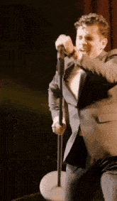 a man in a suit singing into a microphone on stage