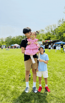 a little girl in a pink dress is being held by a boy