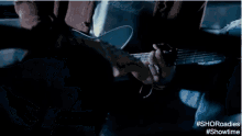 a man is holding another man 's hand in a dark room with #showtime written on the bottom