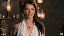 a woman with a tattoo on her arm is wearing a white top and a necklace