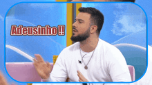 a man with a beard is sitting in front of a sign that says adeusinho