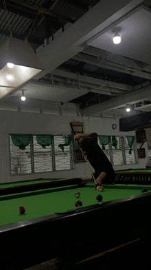 a man is playing pool in a room with a pool table that says spot billiards