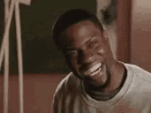 a man is laughing and looking at the camera while wearing a sweatshirt .