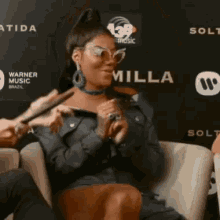 a woman wearing sunglasses is sitting in front of a wall with the word milla on it