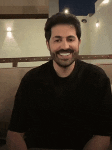 a man with a beard wearing a black shirt smiles