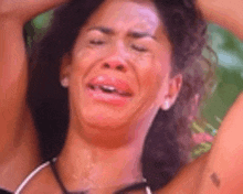 a woman is crying with her eyes closed and her hands in her hair .
