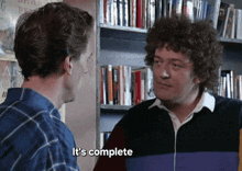 a man says it 's complete in front of a bookshelf