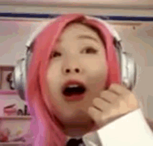 a woman with pink hair is wearing headphones .