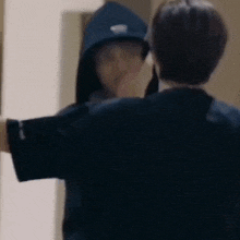 a man in a blue hoodie is standing next to another man in a black shirt .