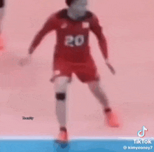 a soccer player wearing a red jersey with the number 20 on it is running on a field .