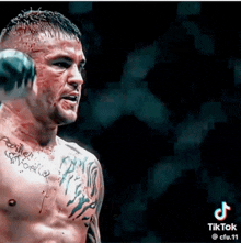 a man with a tattoo on his chest is holding a boxing glove .