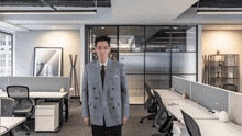 a man in a suit and tie stands in a cubicle in an office