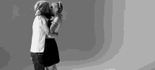 a black and white photo of a man and a woman kissing .