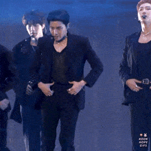 a man in a black suit is standing in front of a group of men in black suits