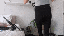 a woman in black leggings is standing in front of a bed in a bedroom .