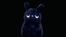 a black stuffed animal with big eyes is surrounded by a rainbow of colors