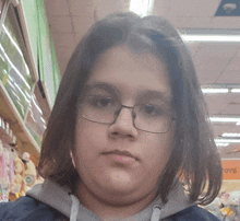 a young boy wearing glasses and a hoodie is looking at the camera