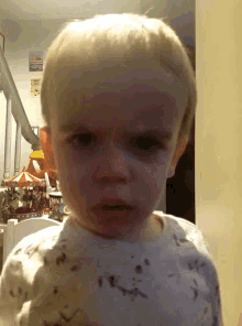 a baby making an angry face in front of a merry go round