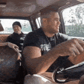 a man wearing a shirt that says 77etics is driving a vehicle