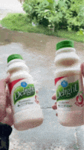 a person is holding two bottles of delight juice