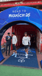 two soccer players are walking through a tunnel with a sign that says road to munich 25
