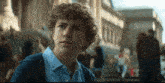 a young man with curly hair looks at the camera